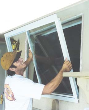 You are about to see a picture Brent installing a replacment window in a typical stucco house. This window is a simple no grids (dividers, mulliuns, cris cross squares , what ever you want to call'em).  This is a simple installation, Brent will take about a hour per window. Windows with brick, wood, shutters or any thing like that will take just about 10 minutes longer. On those windows he needs to trim the edge of the window flange to fit. The result is a great looking window that ties into your wood or bricks ect.